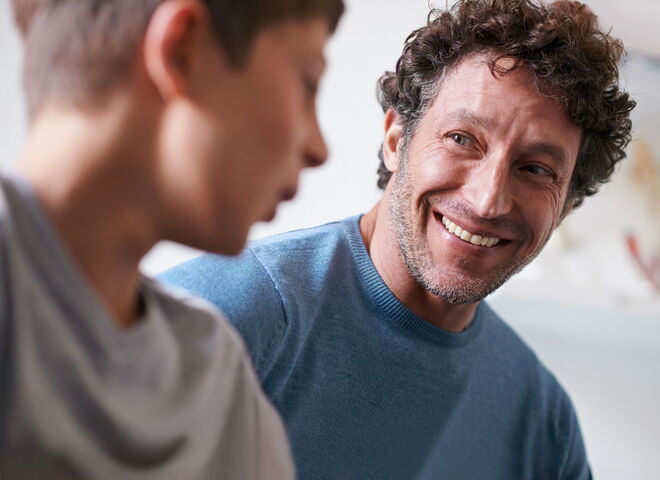 Ein Betreuer hört einem Jungen freundlich während eines Gesprächs zu.